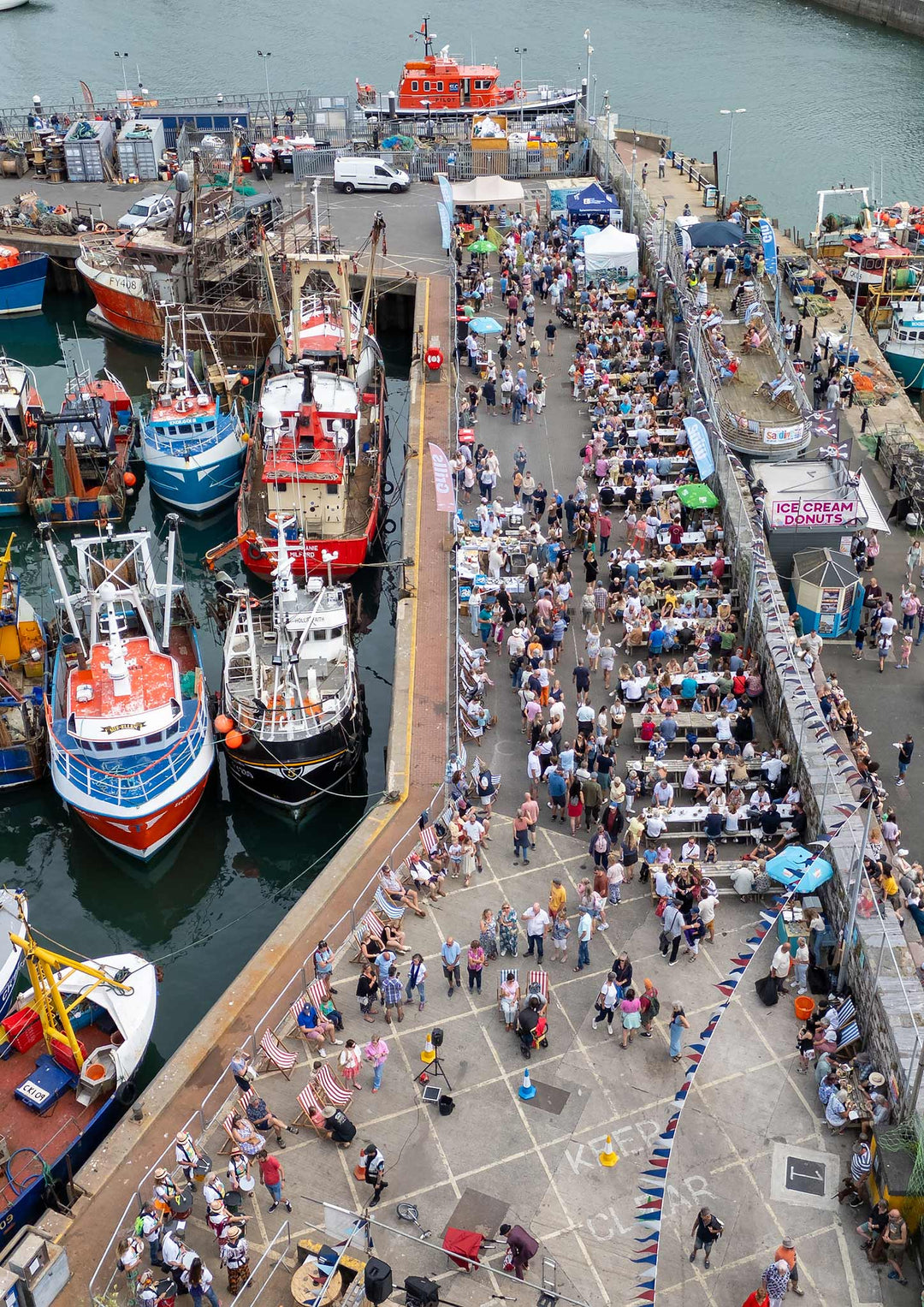 Fishing boats and festival tables along Brixham Harbour at the South West Sardine Festival