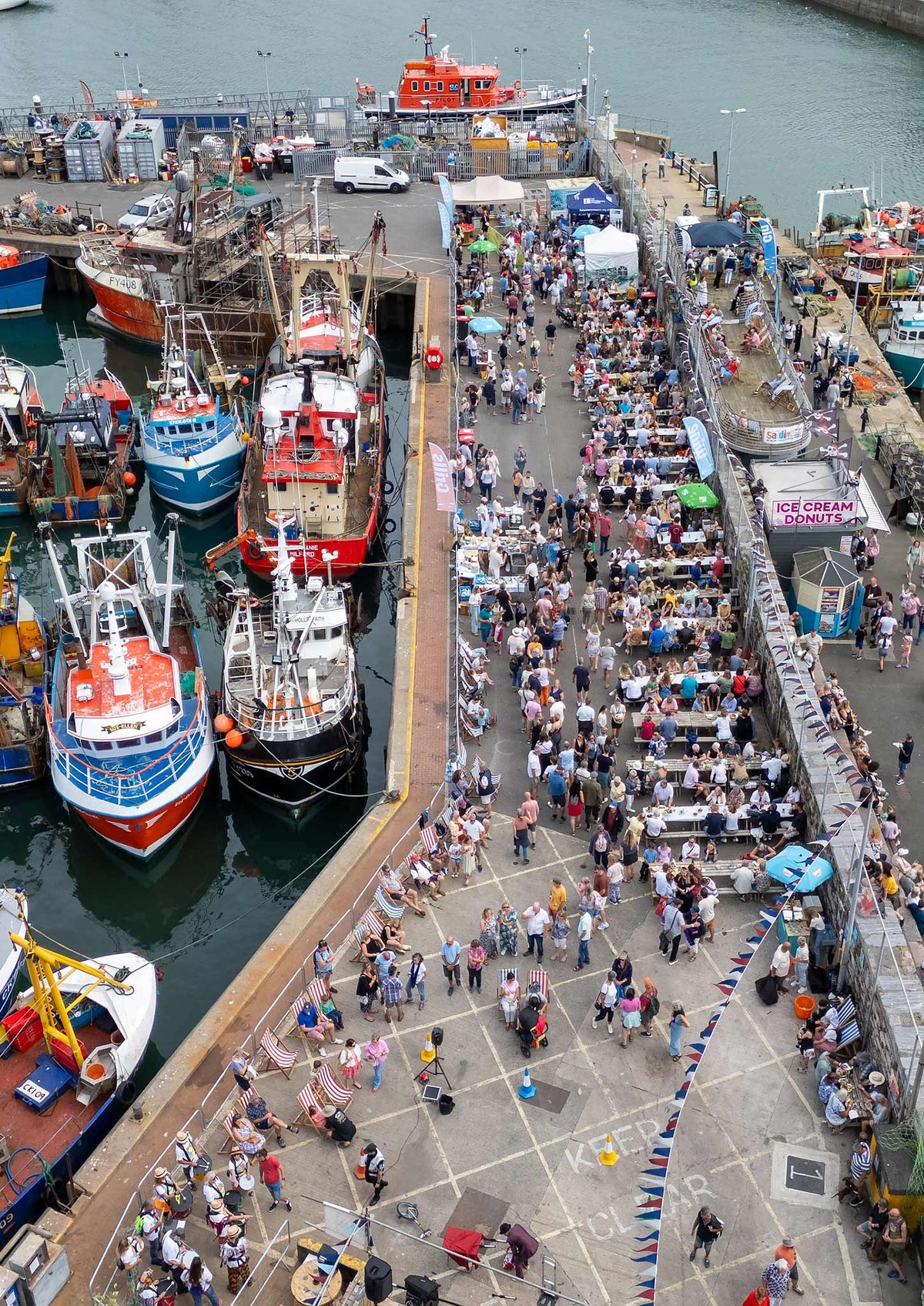 Fishing boats and festival tables along Brixham Harbour at the South West Sardine Festival